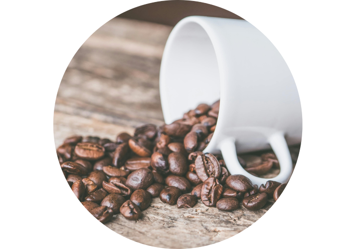 A coffee cup laying on it's side with coffee beans spilling out